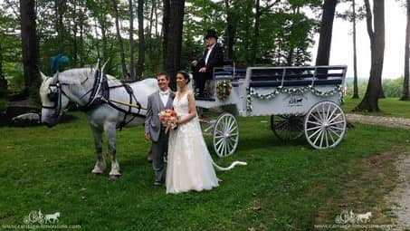 Bride and groom posing with the Limousine carriage at Seven Springs